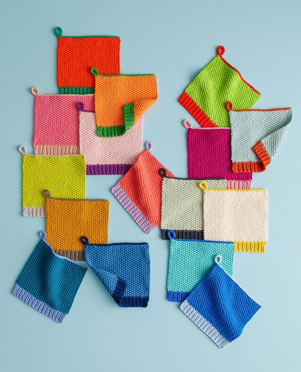 colorful knitted items are arranged on a light blue background, with one folded up and the other unzipped