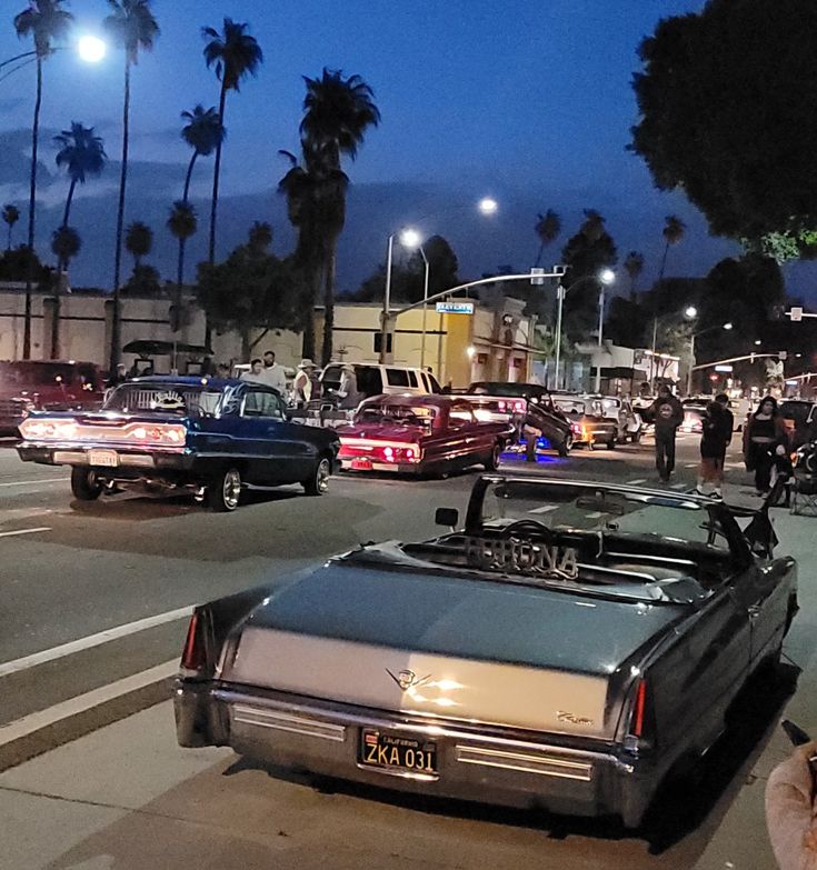 an old car is parked on the side of the road in front of other cars