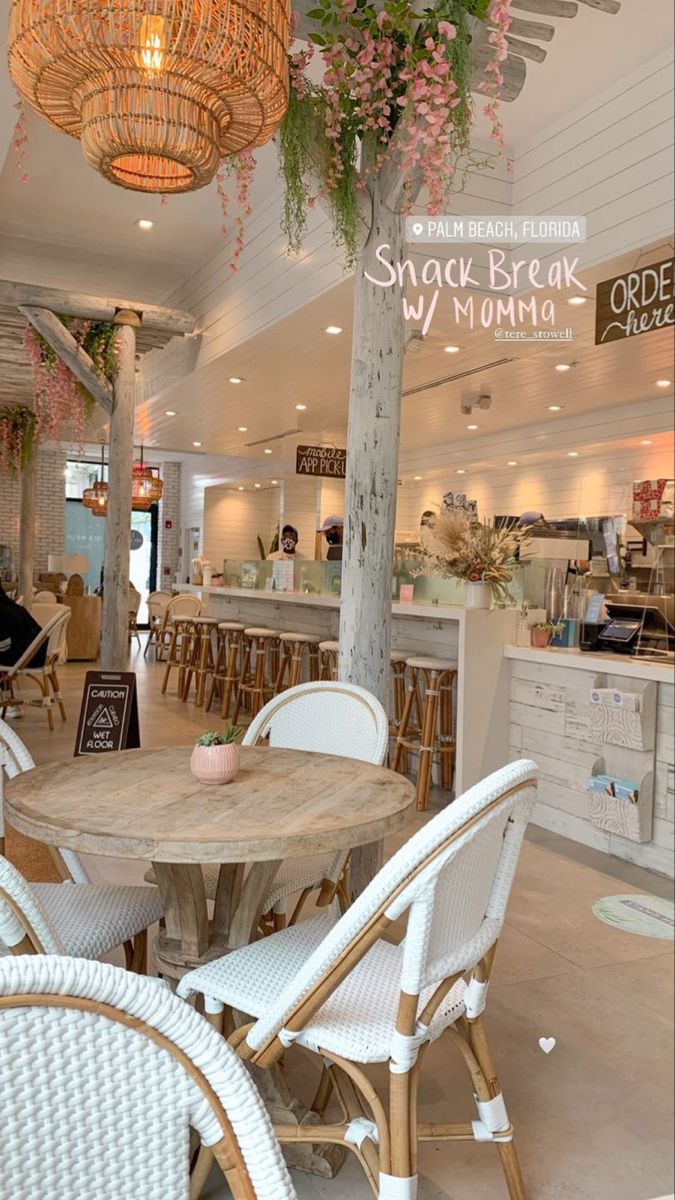 the inside of a restaurant with tables, chairs and plants hanging from the ceiling above