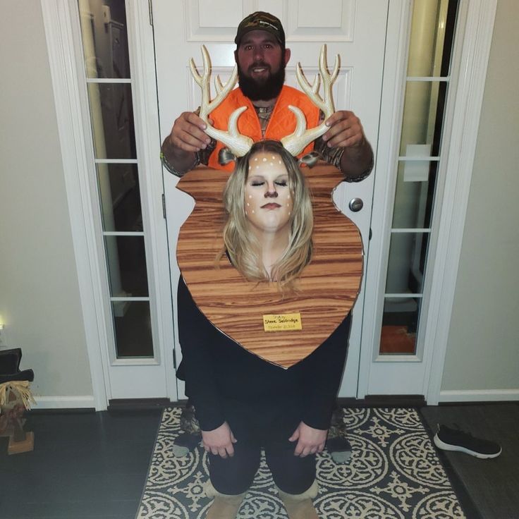 a man standing next to a woman with deer antlers on her head in front of a door