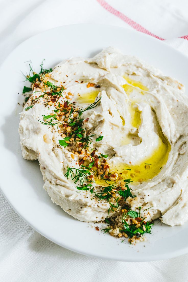 a white plate topped with hummus and herbs