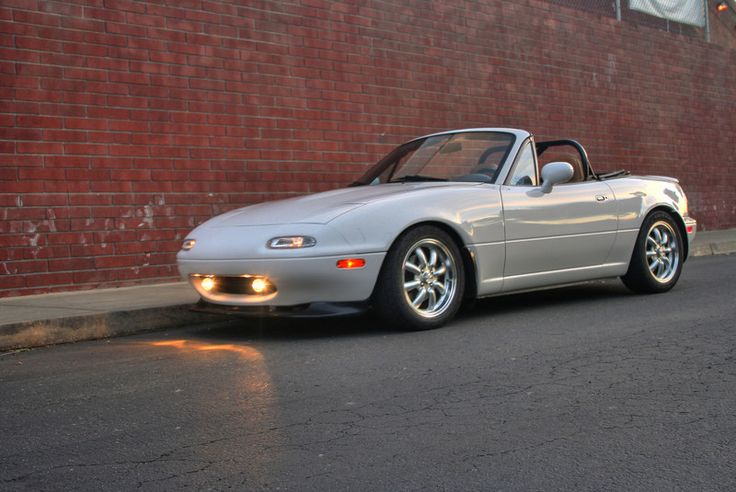 a silver sports car parked next to a brick wall in front of a red building