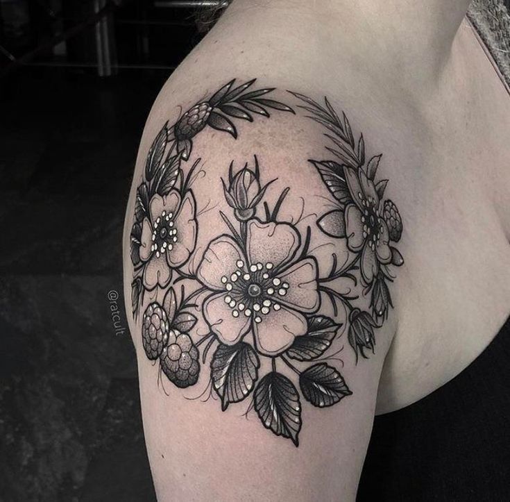 a woman's shoulder with flowers and leaves on her left arm, in black ink