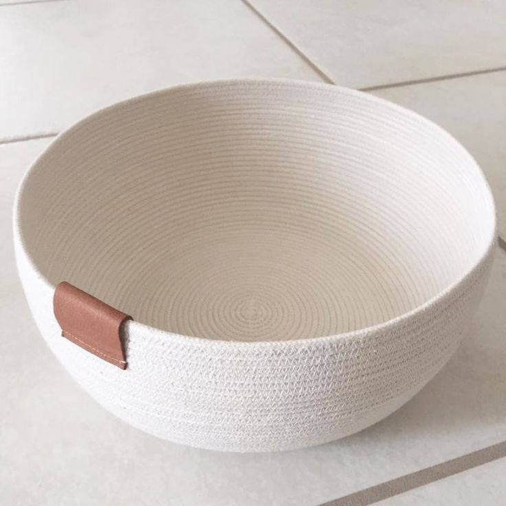 a white bowl with a brown handle on the floor