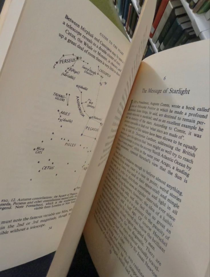 an open book sitting on top of a table in front of a bookshelf