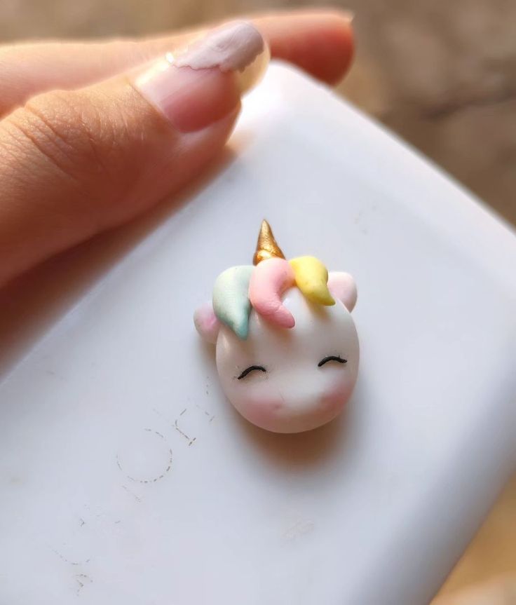 a tiny toy with a unicorn's head on it is being held by someone