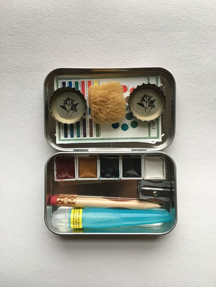 two tins with toothbrushes, brushes and other items in them on a white surface