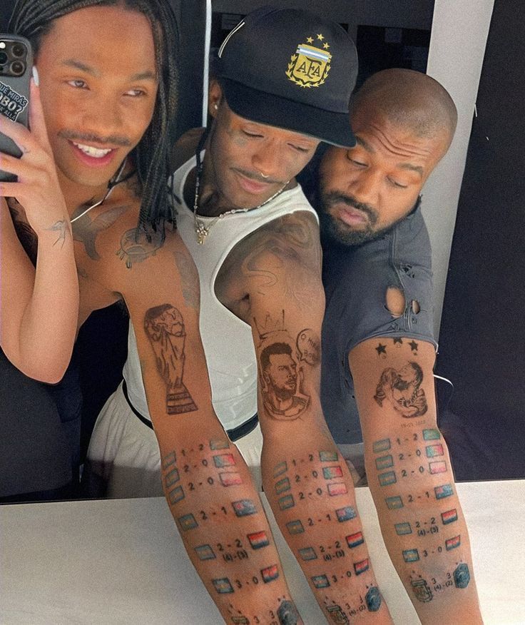 three people with tattoos on their arms taking a selfie