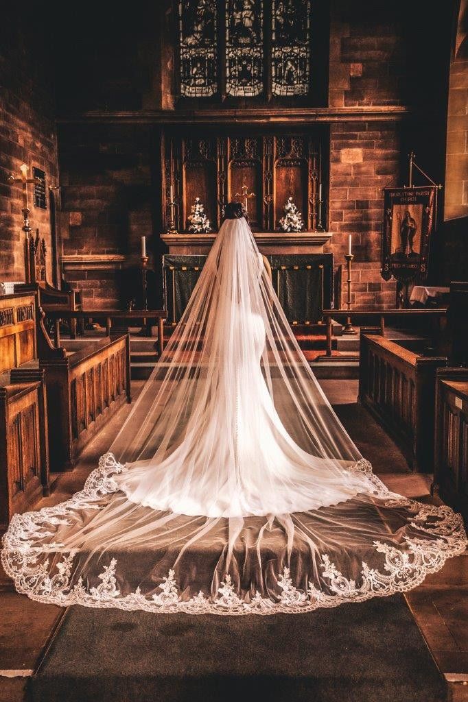 a bride's veil is draped over her wedding dress at the alter in an old church