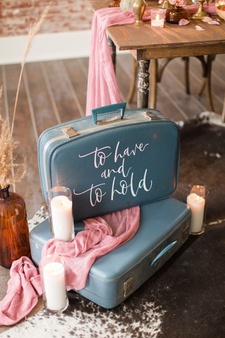 a blue suitcase sitting on top of a table next to some candles and other items