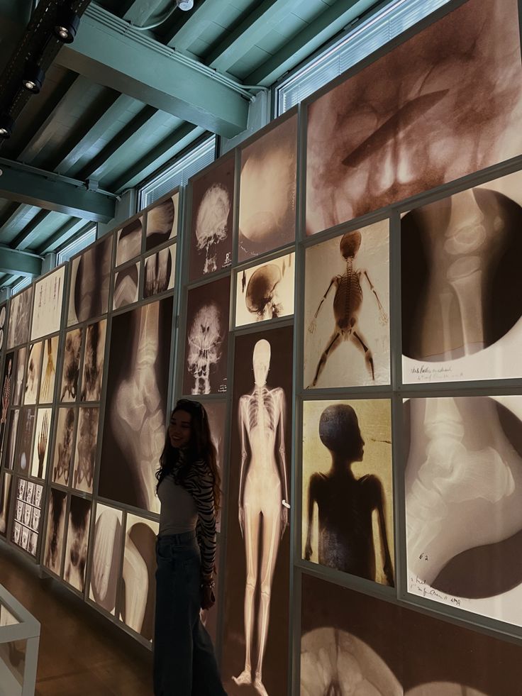 a woman standing in front of a wall with pictures on it