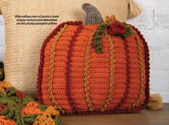 a crocheted pumpkin sitting on top of a pillow