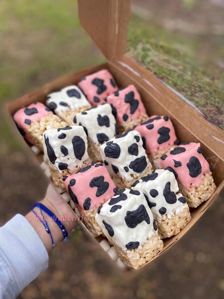 a box filled with cookies covered in pink and black cow print frosted icing