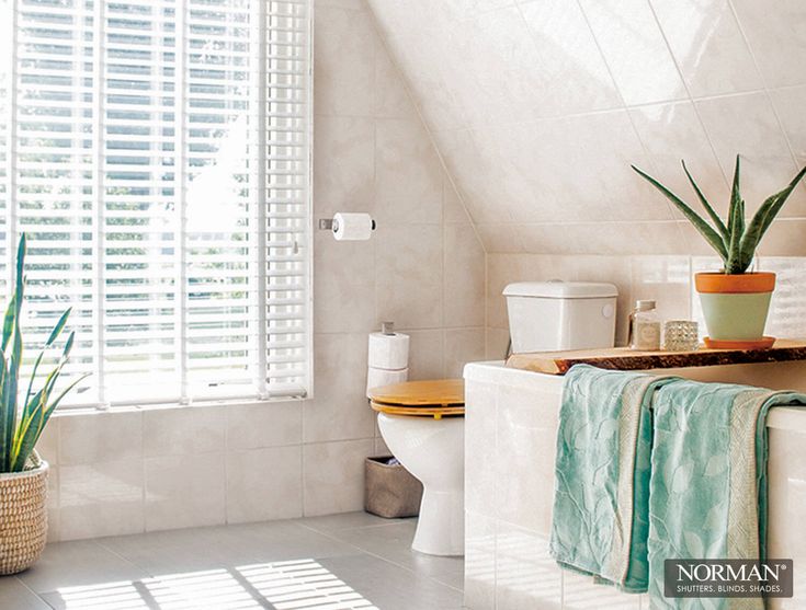 a bathroom with a toilet, sink and plants in it