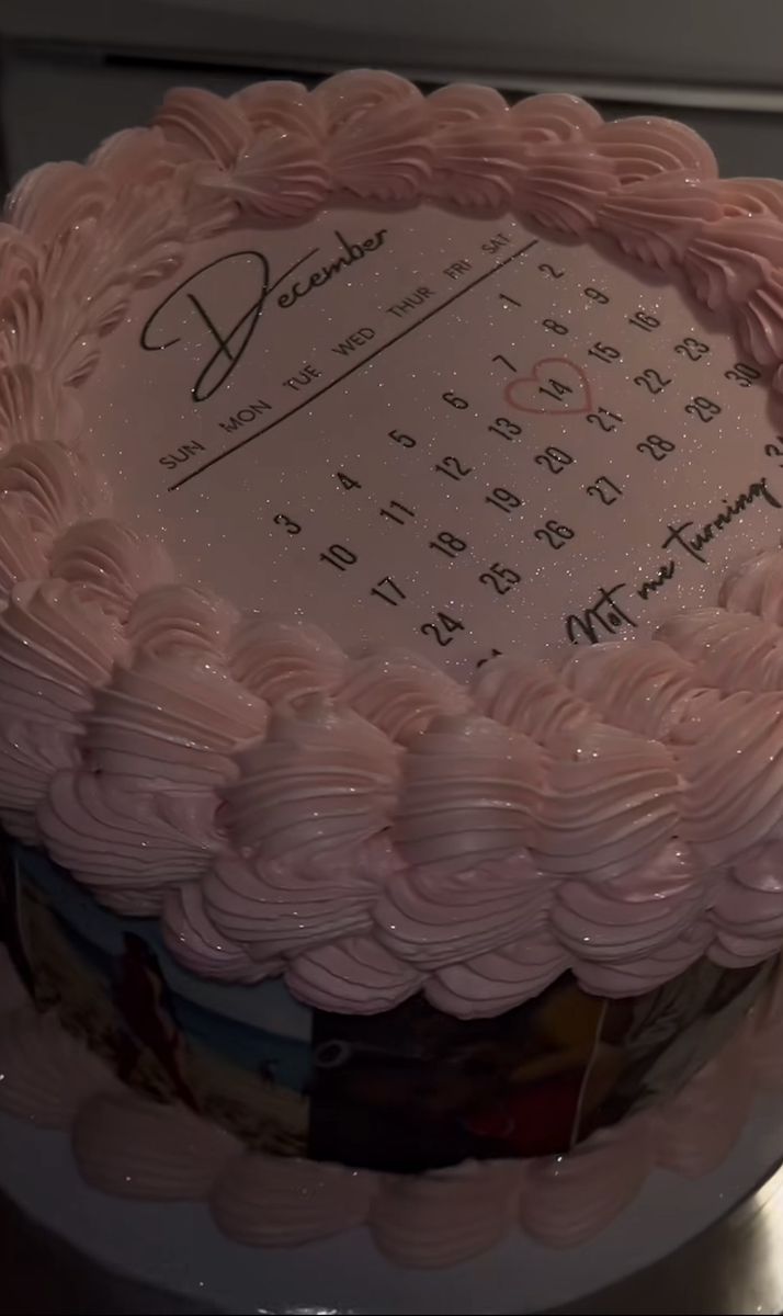 a large pink cake sitting on top of a table next to a microwave oven with writing on it