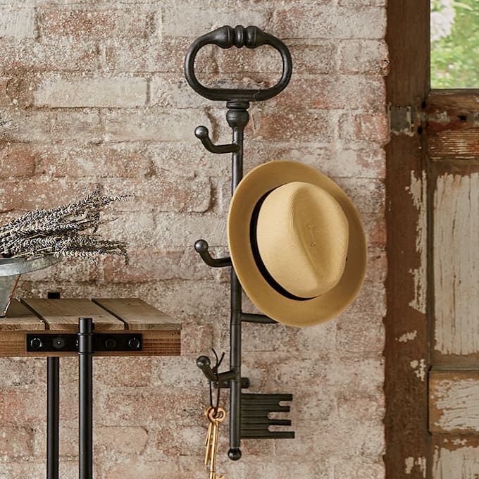 a hat is hanging on a coat rack next to a brick wall with a door