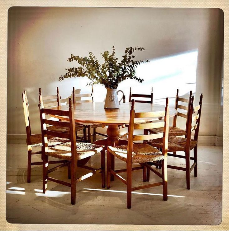 a wooden table with chairs around it and a vase filled with flowers on the top