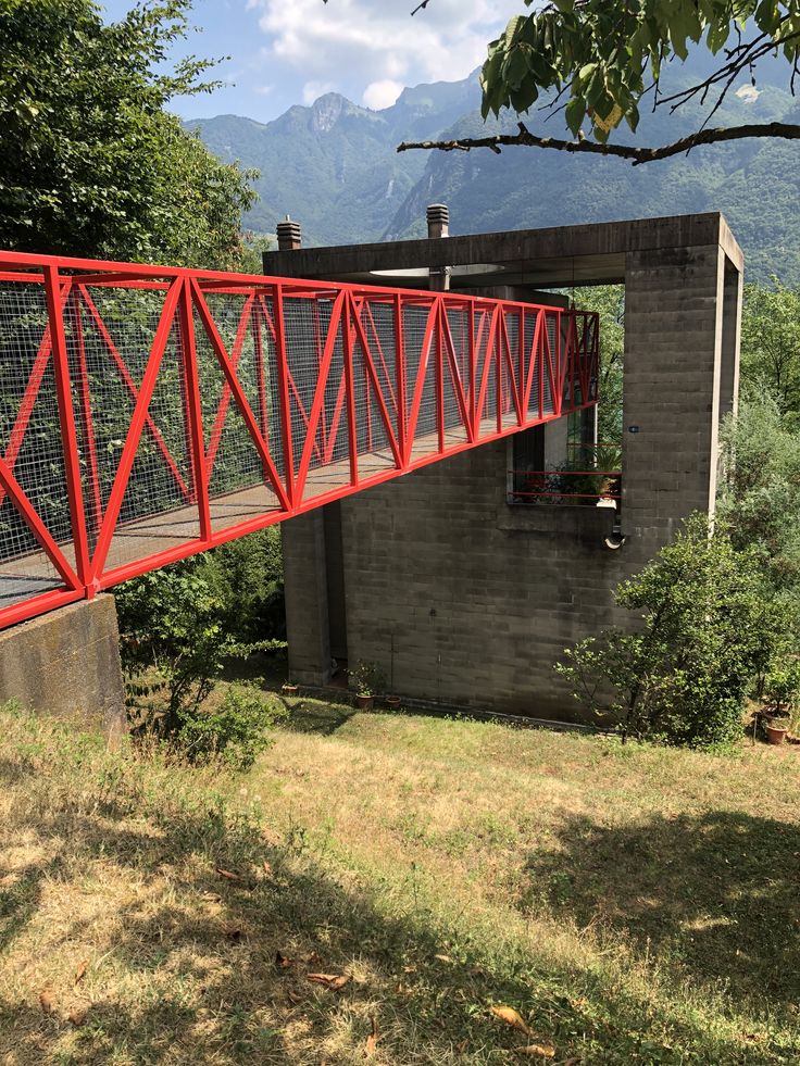 a red metal bridge crossing over grass and trees