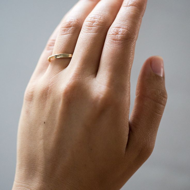 a woman's hand with a gold ring on her left thumb and the middle finger