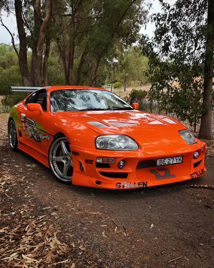 an orange sports car parked in the woods