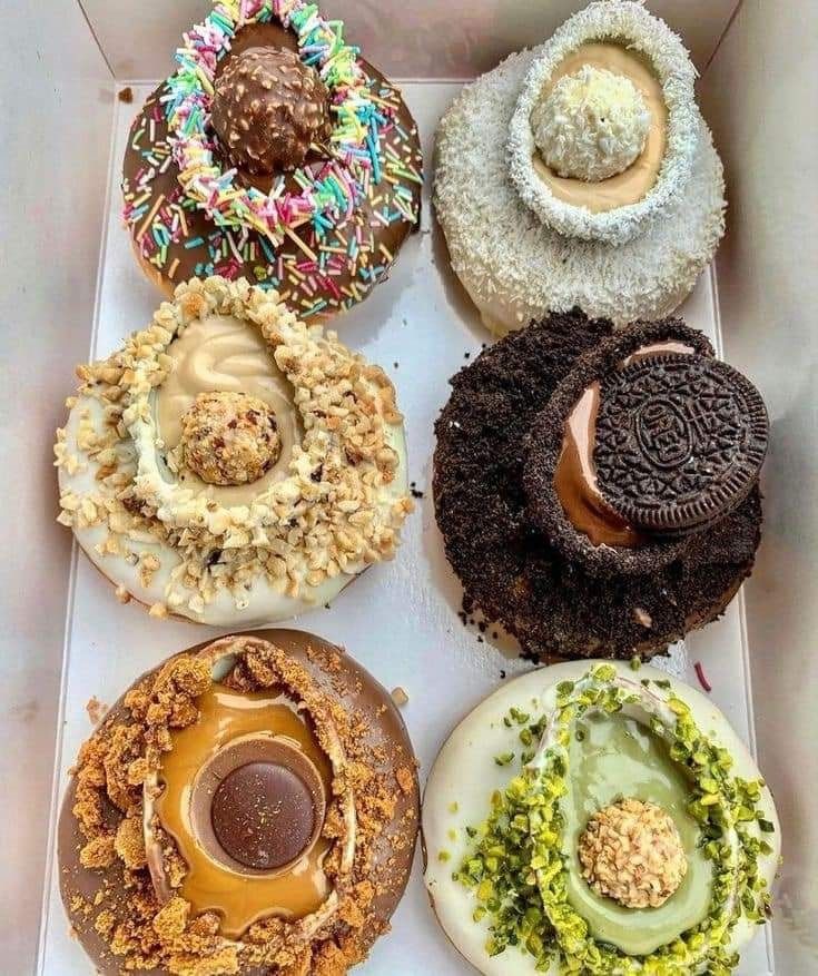 four different types of doughnuts in a box with frosting and sprinkles