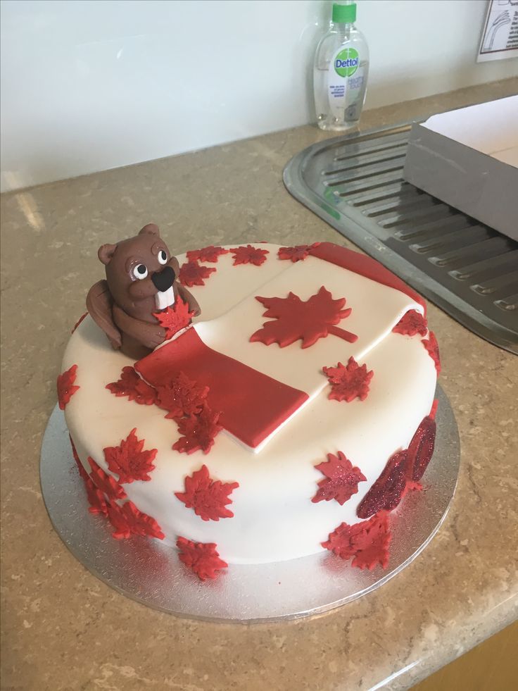 a cake decorated with red maple leaves and a bear on the top is ready to be cut