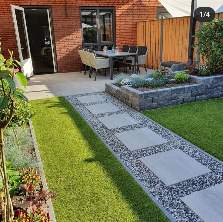 a patio with grass and stone walkways next to a brick building on the other side