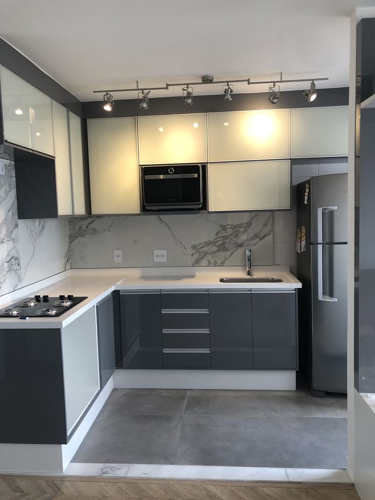 a kitchen with gray and white cabinets, marble counter tops, and stainless steel appliances