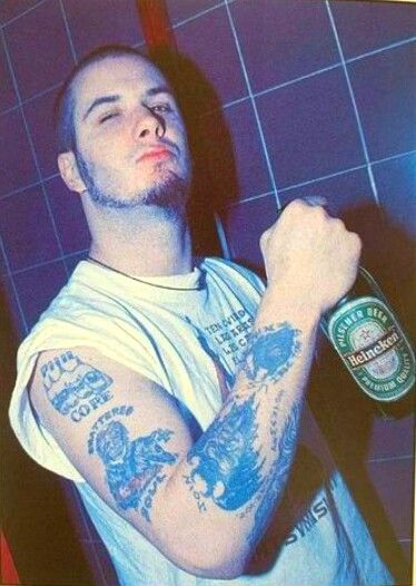 a man with tattoos holding a beer bottle