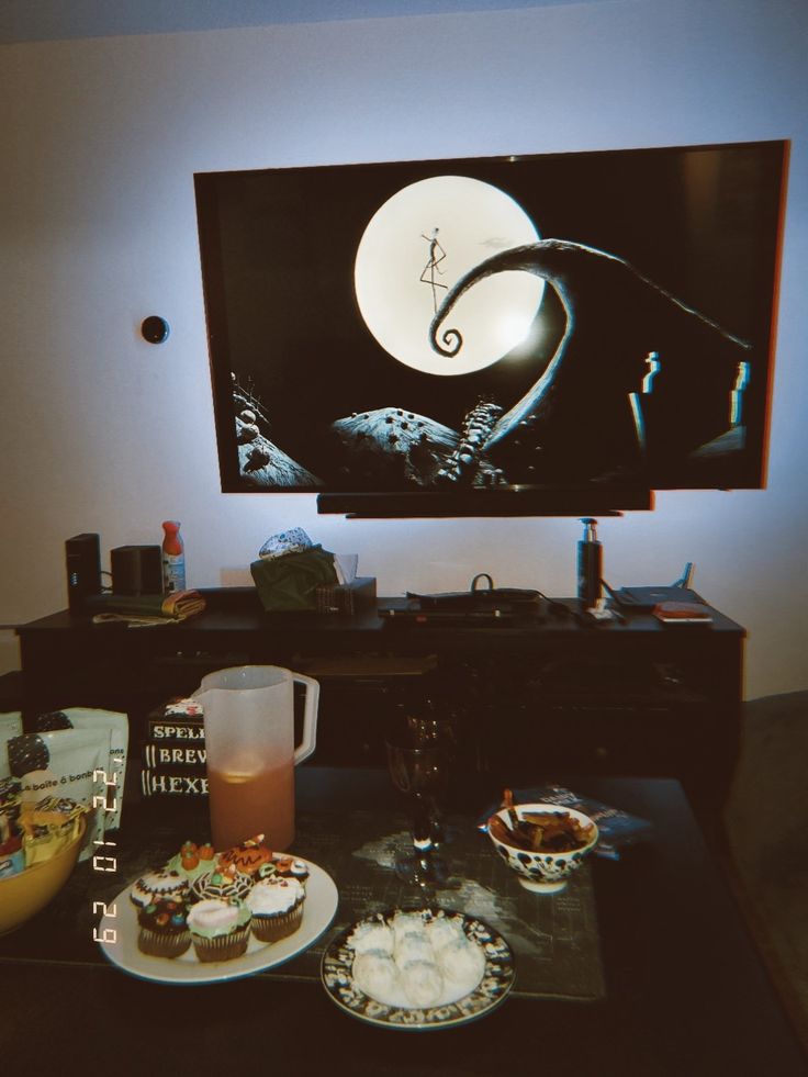 a table topped with plates of food next to a flat screen tv mounted on the wall