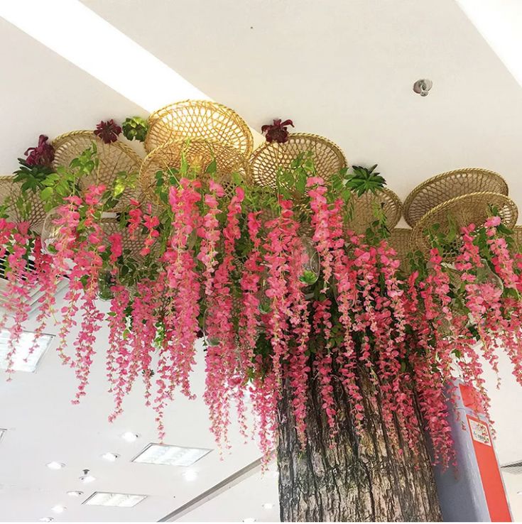 pink flowers are hanging from the ceiling in an office building with wicker chairs around it