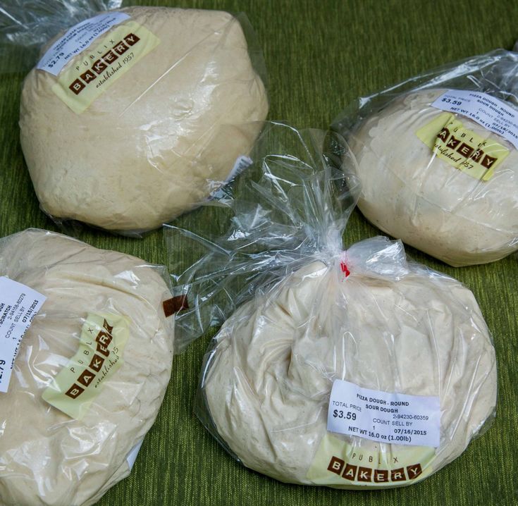 bread wrapped in plastic sitting on top of a green cloth covered table next to each other