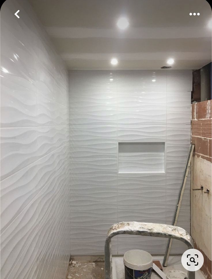 a bathroom with white walls and tile on the floor, including a shower head in the corner