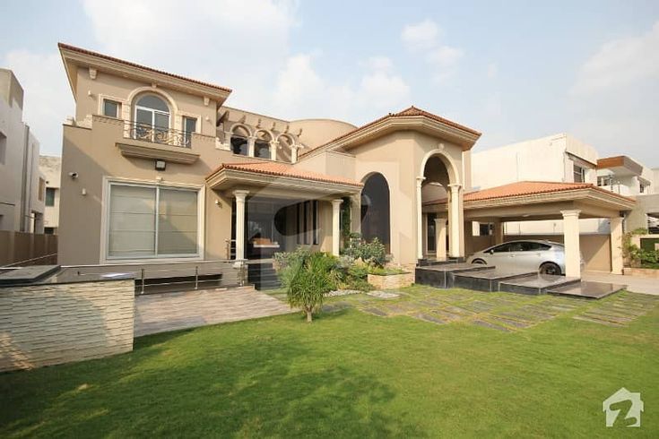 a car is parked in front of a large house with an attached driveway and garage