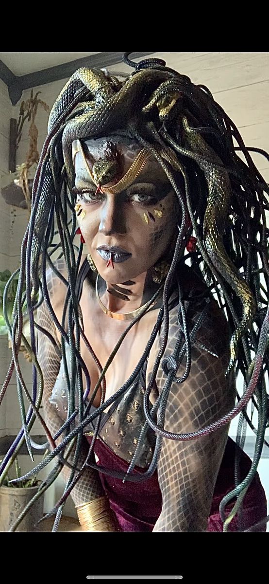 a woman with long hair and snake skin on her face is dressed as a creature