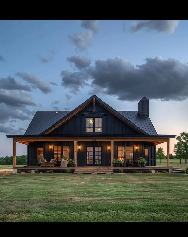 a large house with a porch and covered in windows on the front lawn at dusk