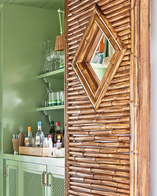 a kitchen with green walls and shelves filled with bottles on top of the countertop