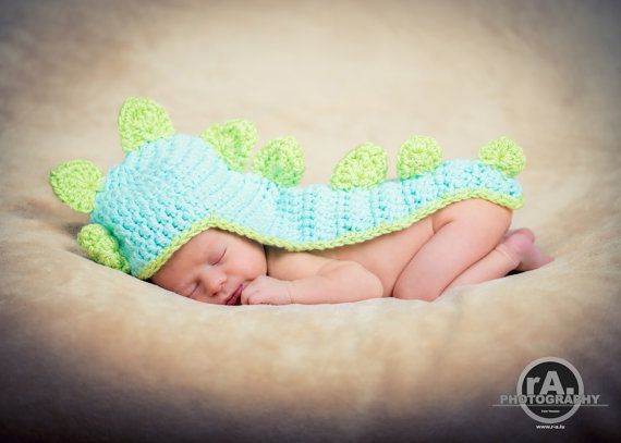 a newborn baby wearing a crocheted green and blue dragon costume sleeping on a blanket