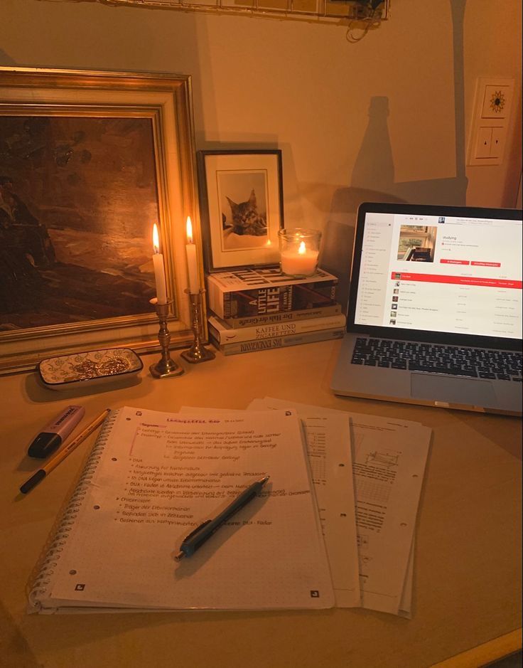 an open laptop computer sitting on top of a desk next to a pen and paper