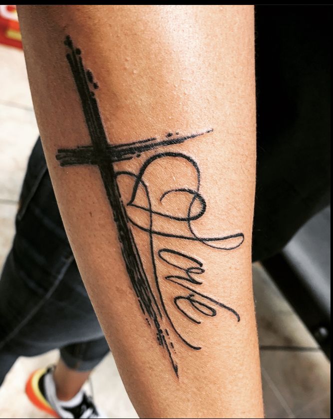 a person with a cross tattoo on their leg and the word faith written in cursive writing