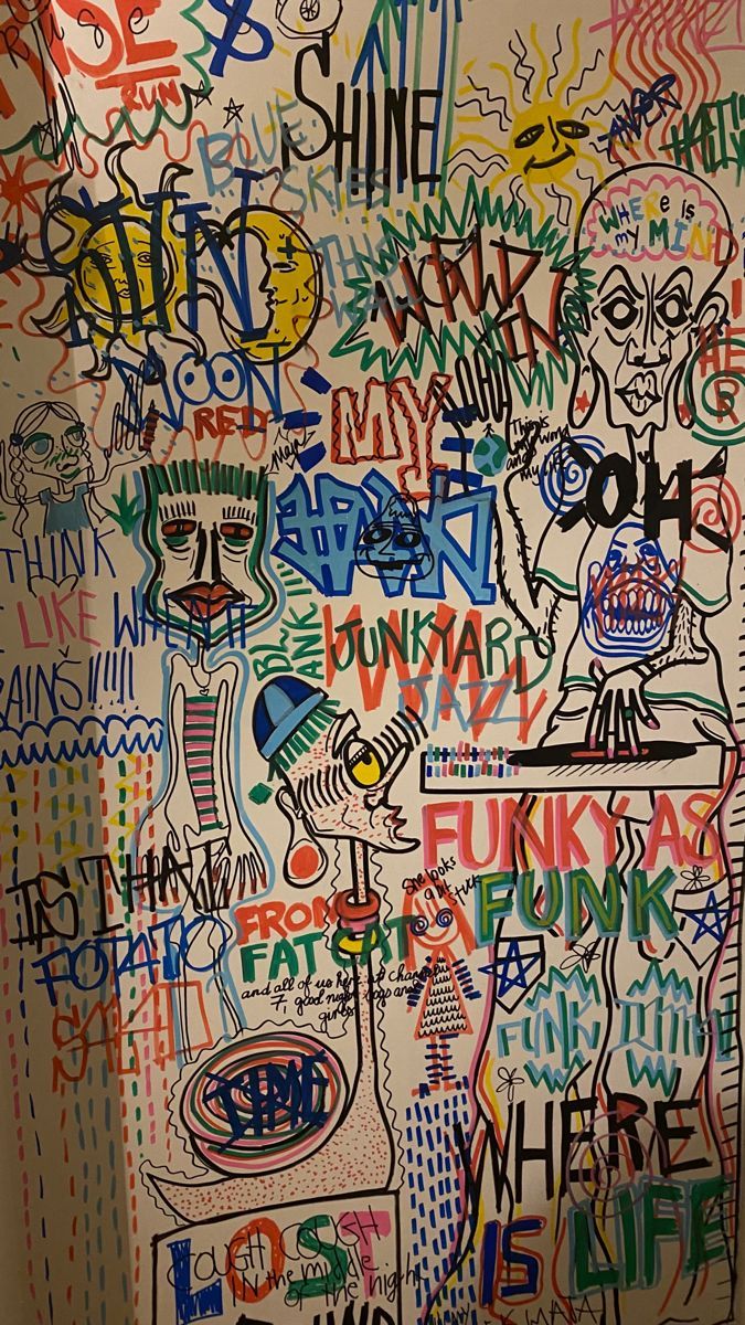 the bathroom wall has many graffiti all over it