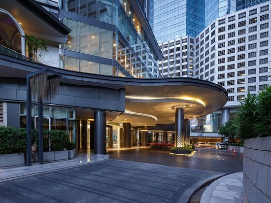 an entrance to a large building with lots of tall buildings in the background at dusk