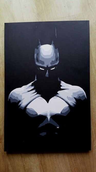 a batman painting on a black canvas with white and grey colors is sitting on a wooden floor