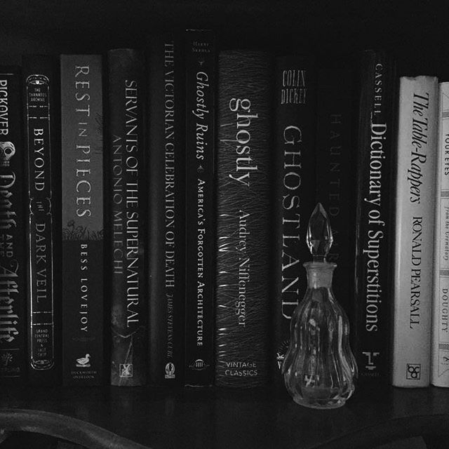 a book shelf filled with lots of books next to a glass vase on top of it