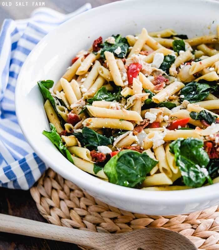 a white bowl filled with pasta and spinach