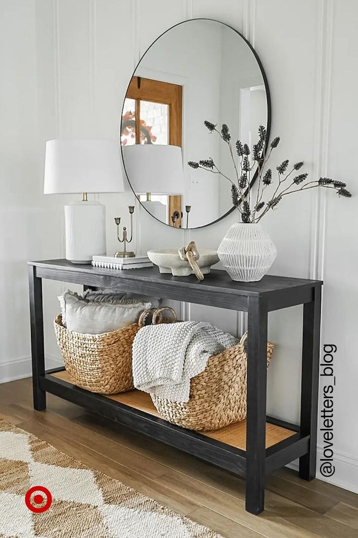 a console table with baskets and a mirror on the wall in a white living room