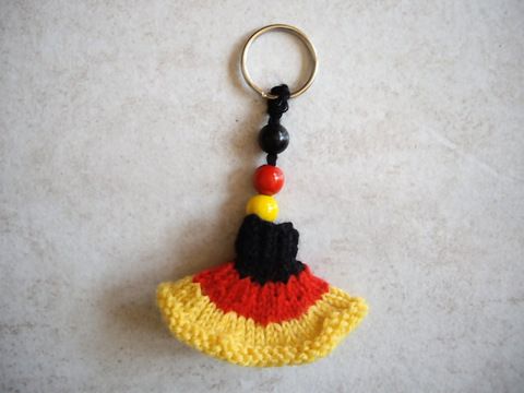 a crocheted keychain with a red, yellow and black hat on it