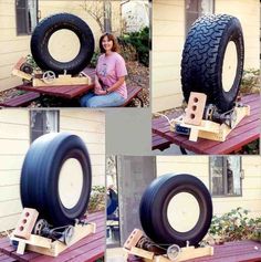 a woman sitting on top of a wooden table next to a giant tire with wheels attached