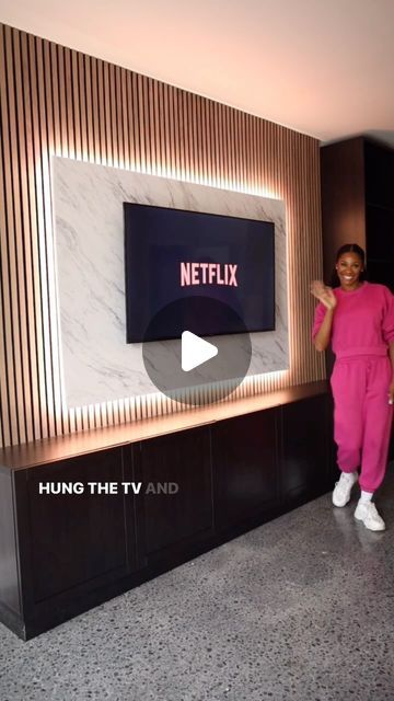 a woman standing in front of a tv with the netflix logo on it's wall