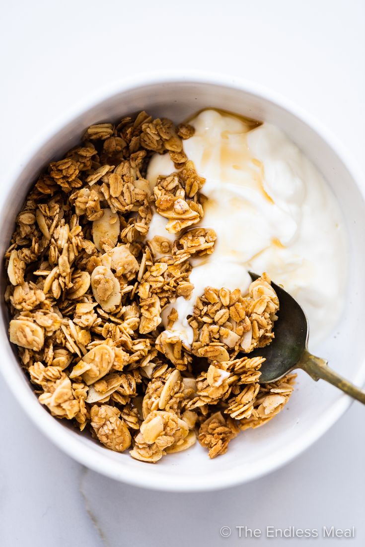 a bowl filled with granola and yogurt on top of a white table